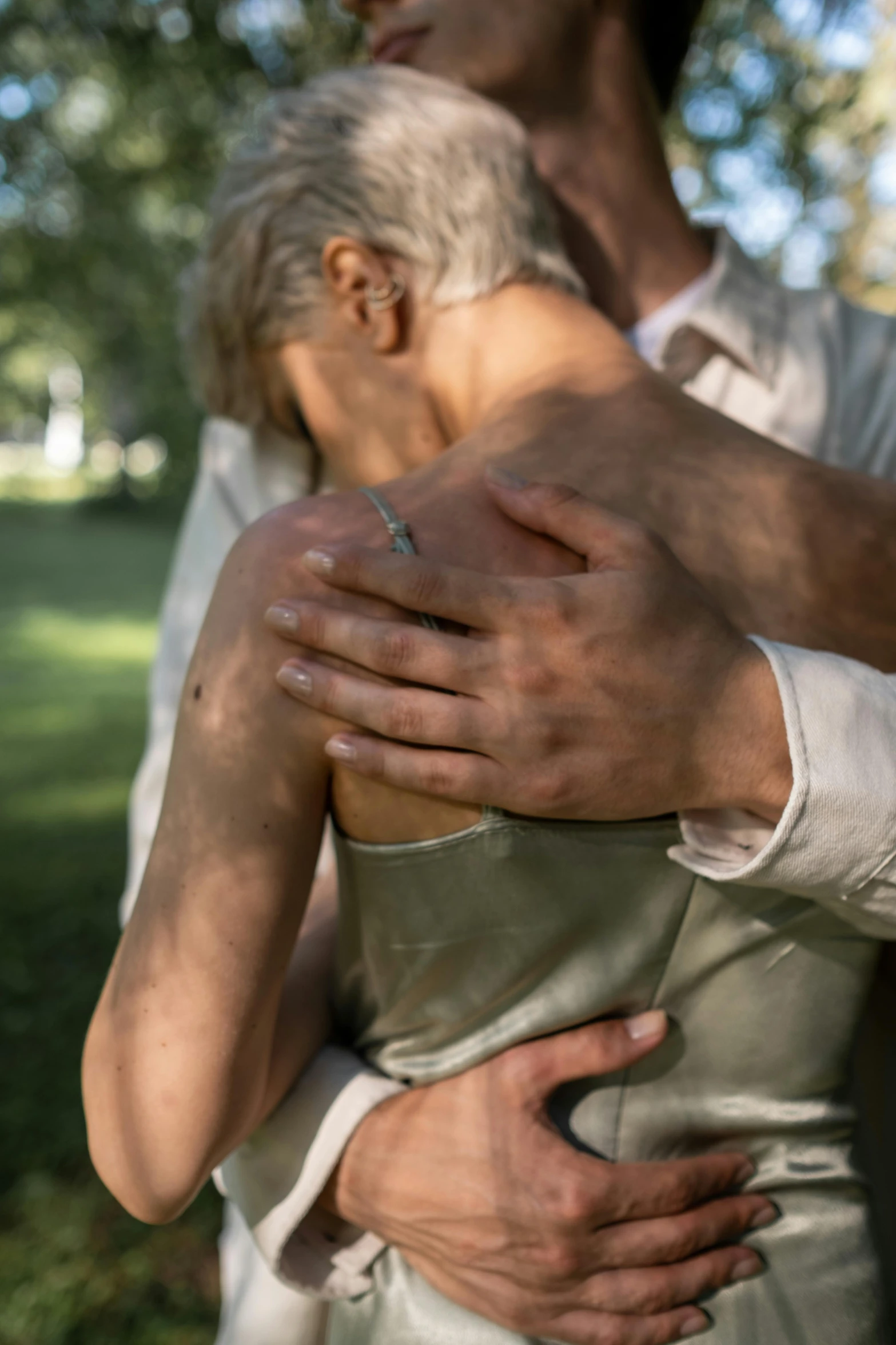 the man holds his hands together while standing in the park