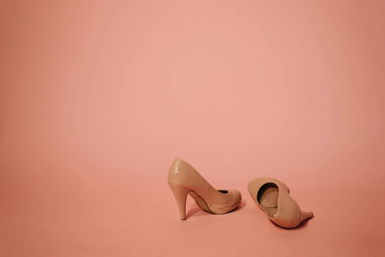 the feet of a pair of  high heeled shoes against a pink background