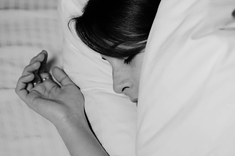 a black and white po of a young person sleeping on the bed