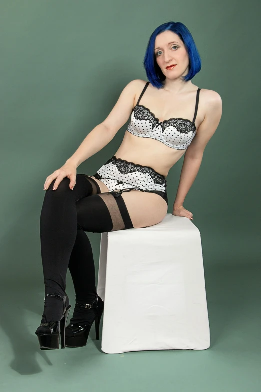 a beautiful young woman wearing lingerie sitting on top of a cube