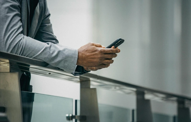 a man is standing at a balcony holding a cellphone