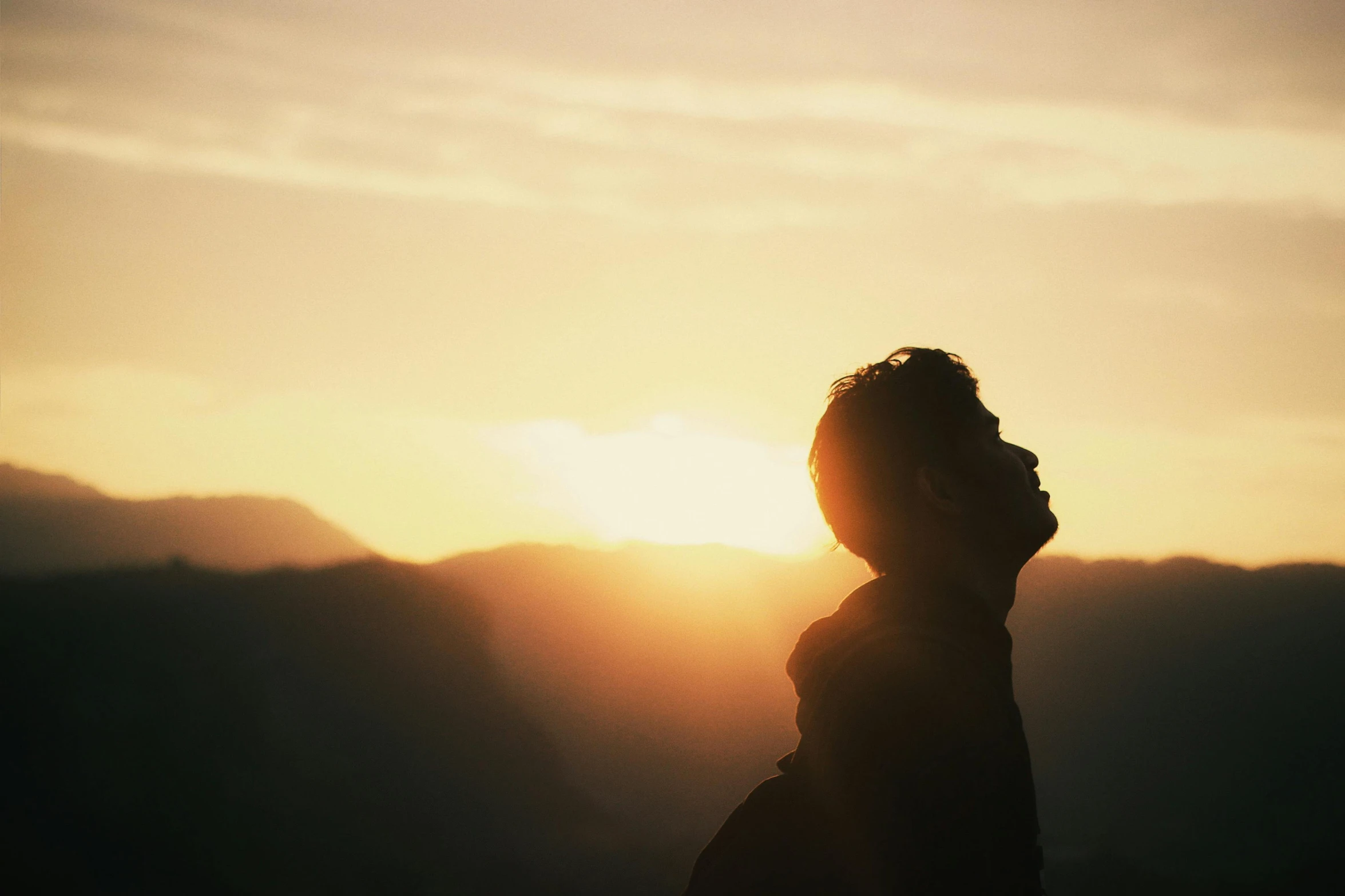 a man standing at the edge of a cliff and watching the sunset