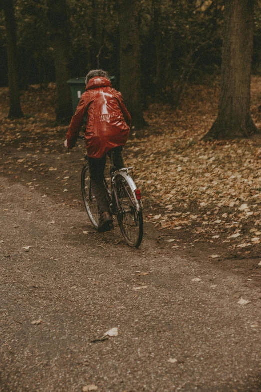 a man in red jacket riding bicycle on dirt road