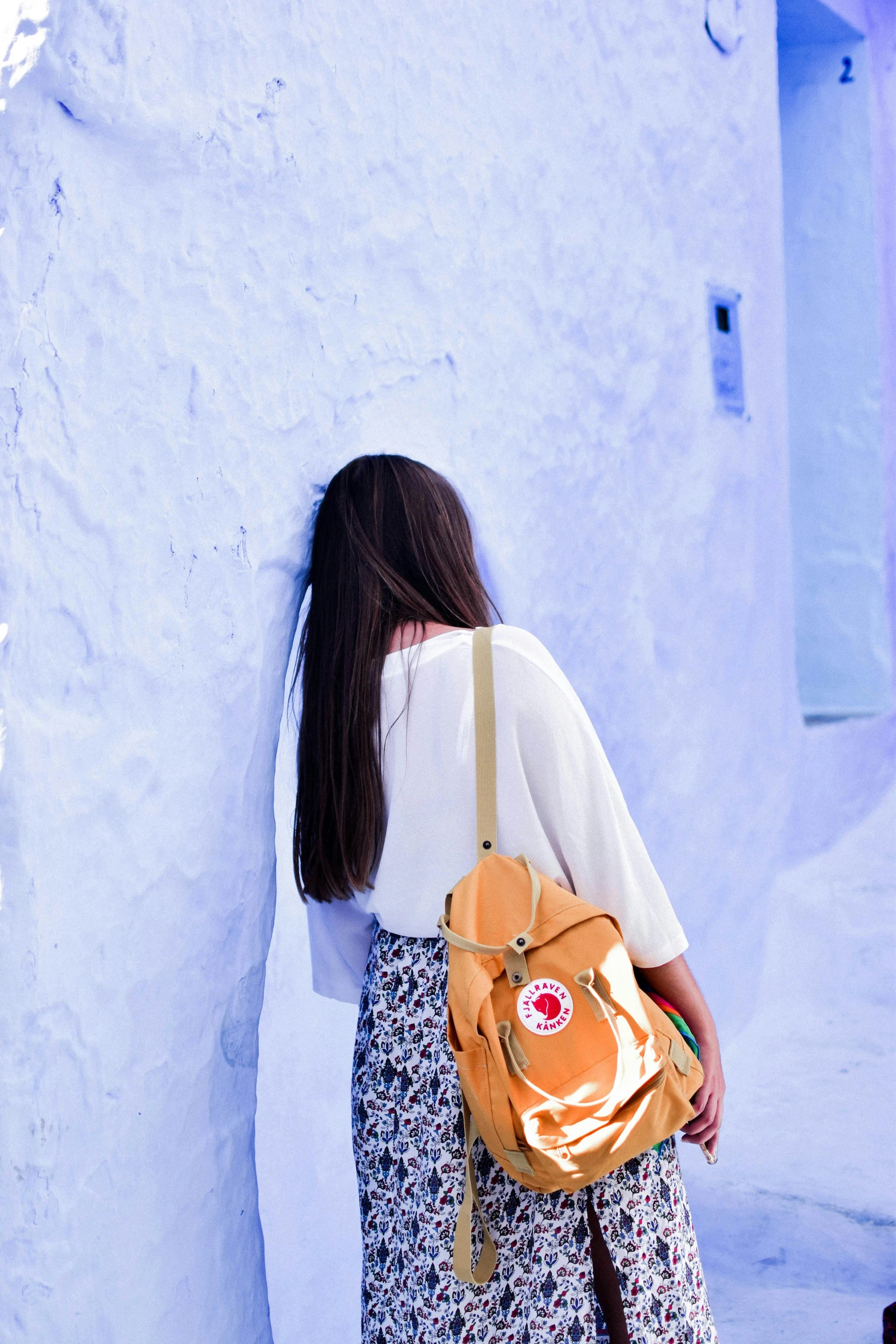 a woman in a white top and a yellow backpack