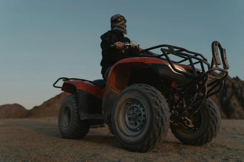 the man is riding his four wheeler in the desert