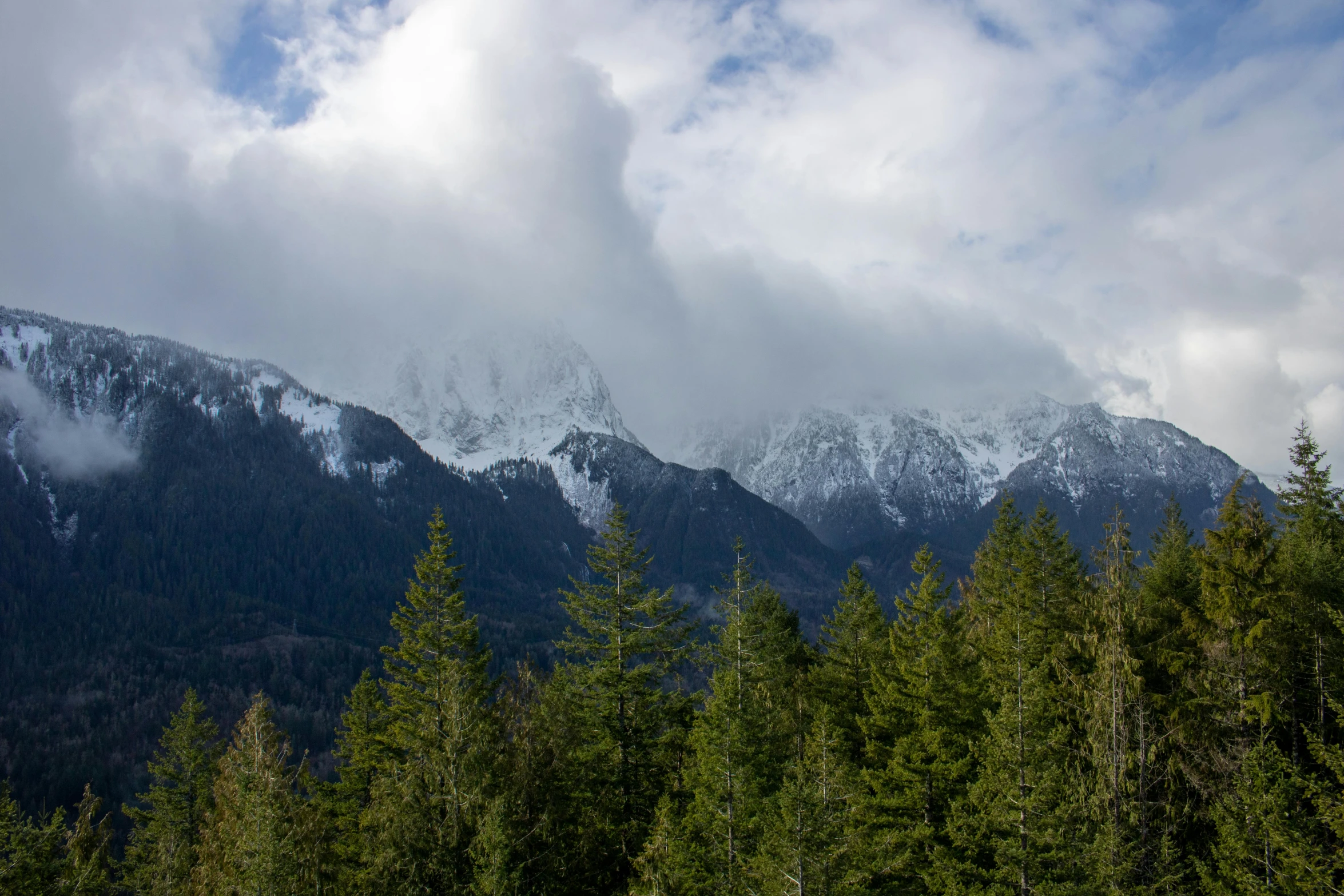 the mountains are covered in snow and clouds