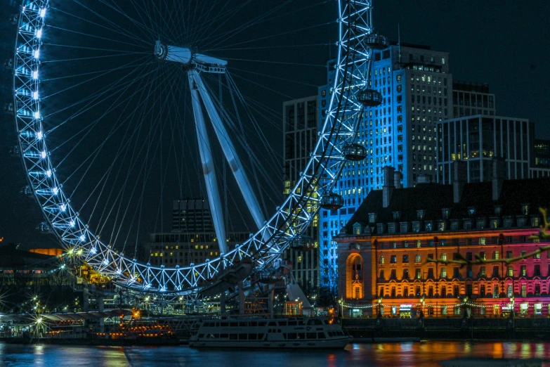 an illuminated ferris wheel at night over a lake