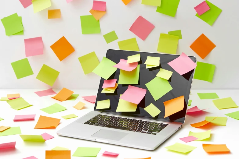 an open laptop computer sitting on top of a white surface covered in sticky notes