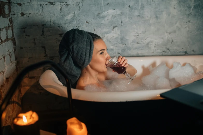 a woman taking a bubble bath and drinking