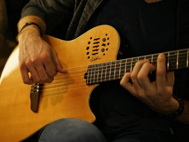 a person sitting down holding a guitar and playing