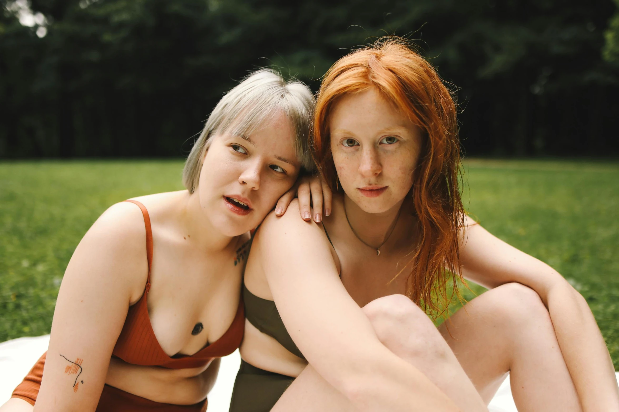 two women sitting next to each other on the ground