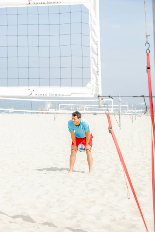 a man standing in the sand holding a volleyball ball