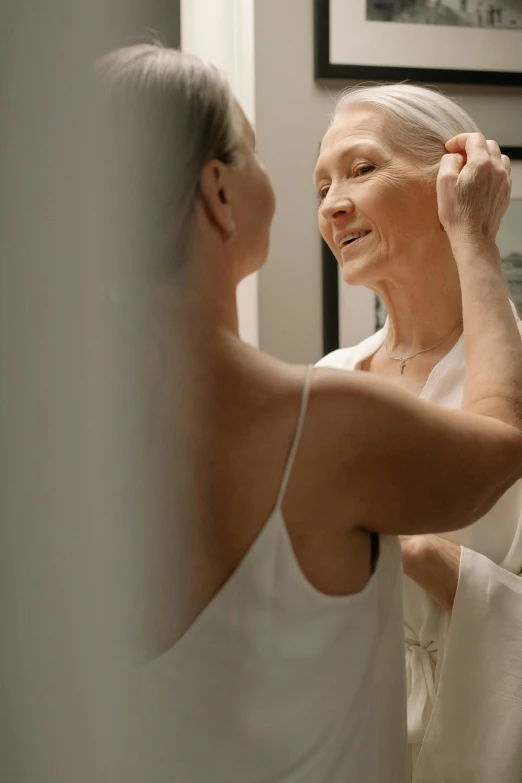 an older woman combs her hair in front of another woman