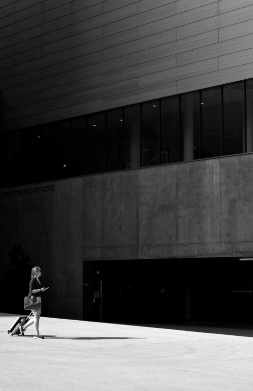 a black and white image of a person walking towards a building