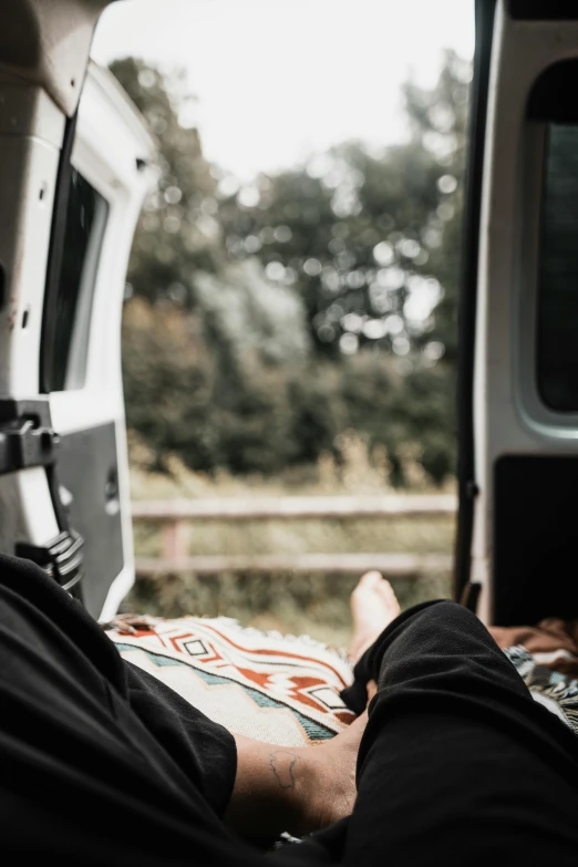 man's legs resting on the ground in front of a van