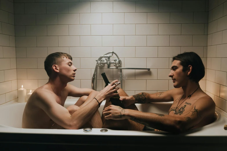 two men are sitting in the tub having their pictures taken