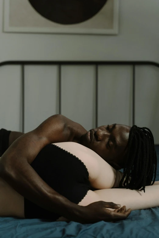 a young woman with dreads lays on a bed
