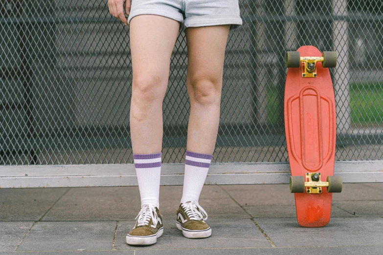 a man with socks and a skateboard stands on the sidewalk