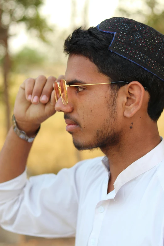 man in white shirt and glasses adjusts tie