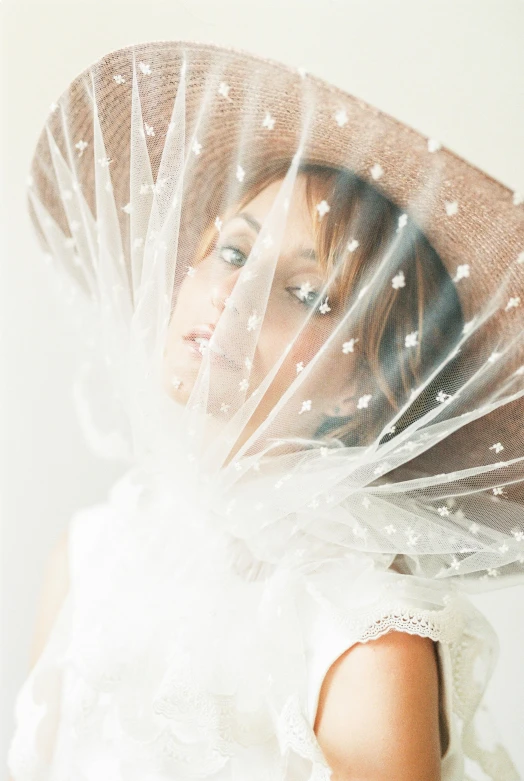 a young woman wearing white dress and hat on her head with veil