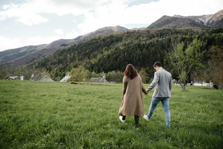 a man and woman are holding hands and walking in the grass