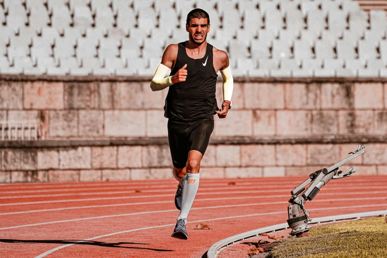 a man in black running on red clay with white walls behind him