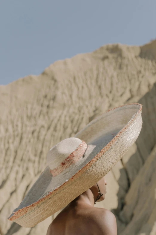 a man holding up a straw hat in front of a mountain