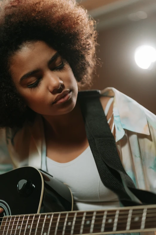 a woman with curly hair is playing the guitar