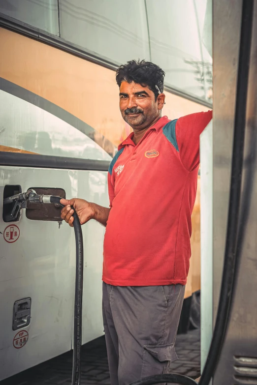 a man standing next to a bus holding a hose