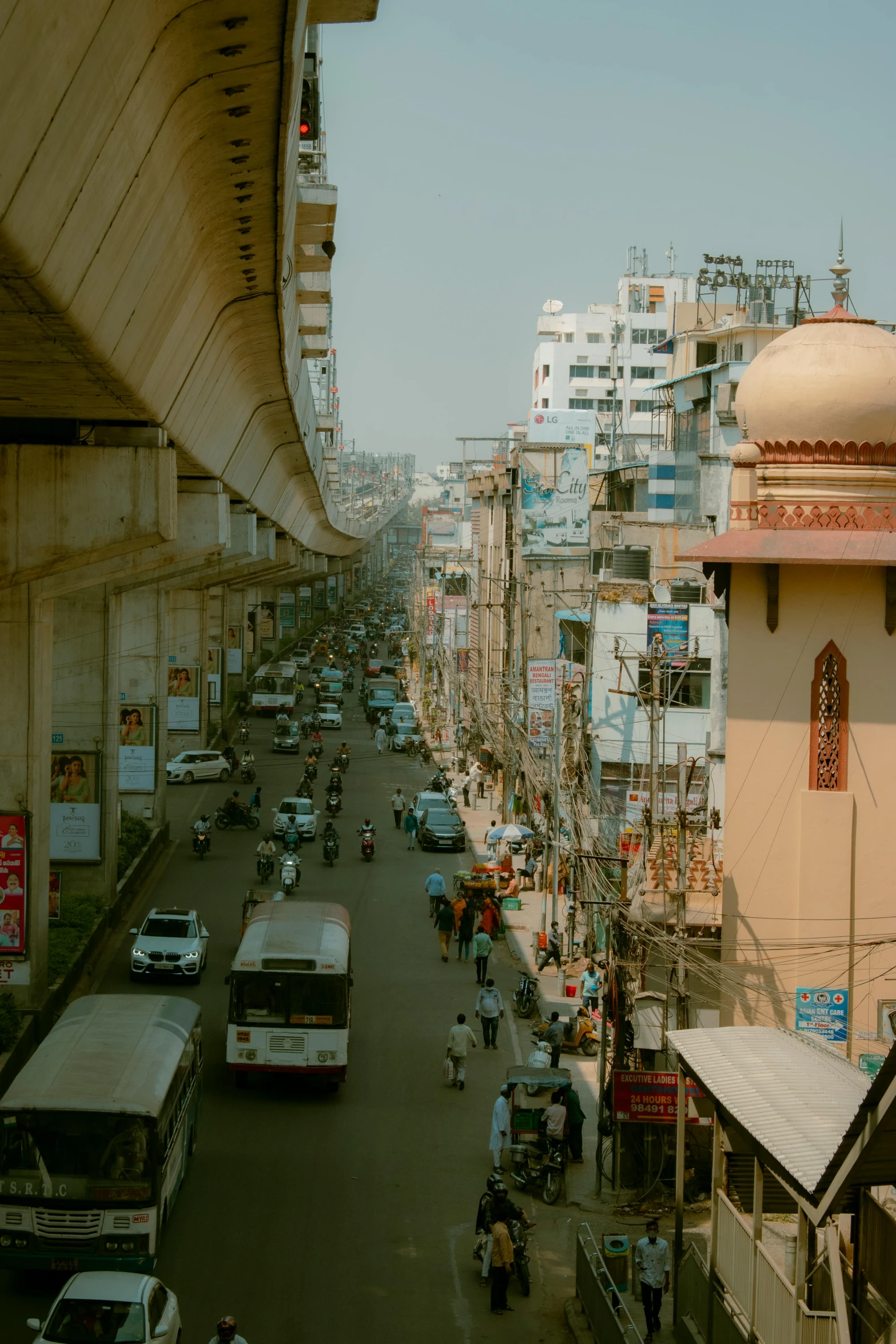 cars and buses drive down a busy street lined with tall buildings