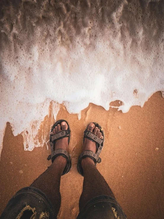 the person has their feet on the sand by the ocean