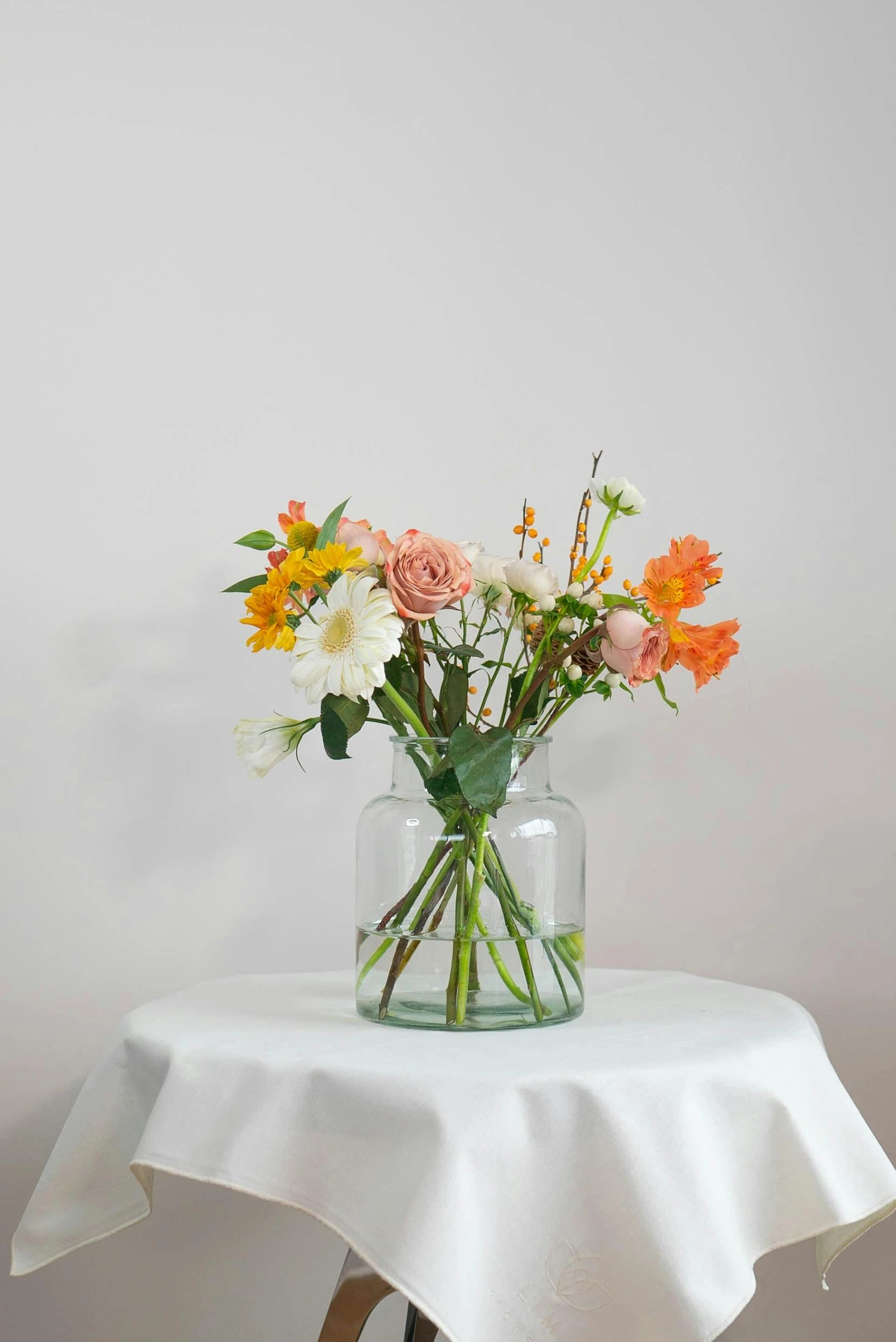 a glass vase of flowers on a small white table