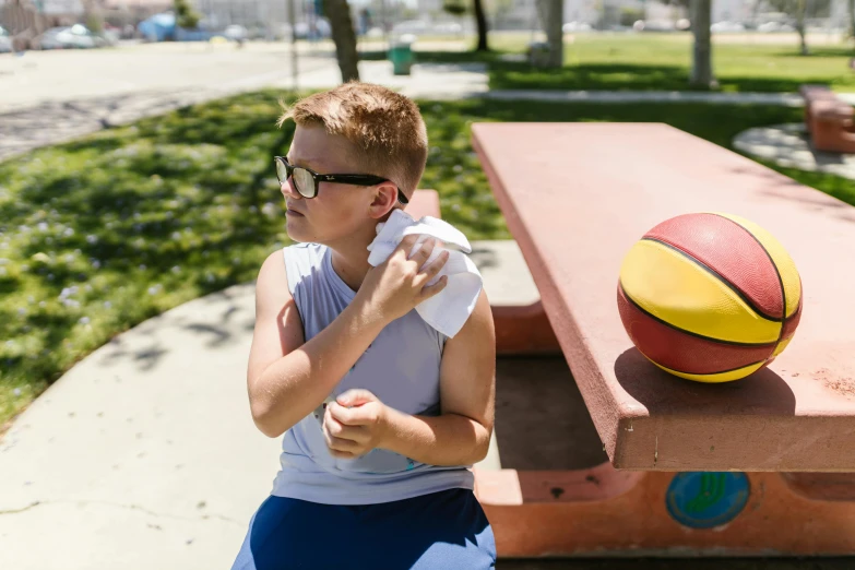 a person blowing their nose with a ball sitting by a table