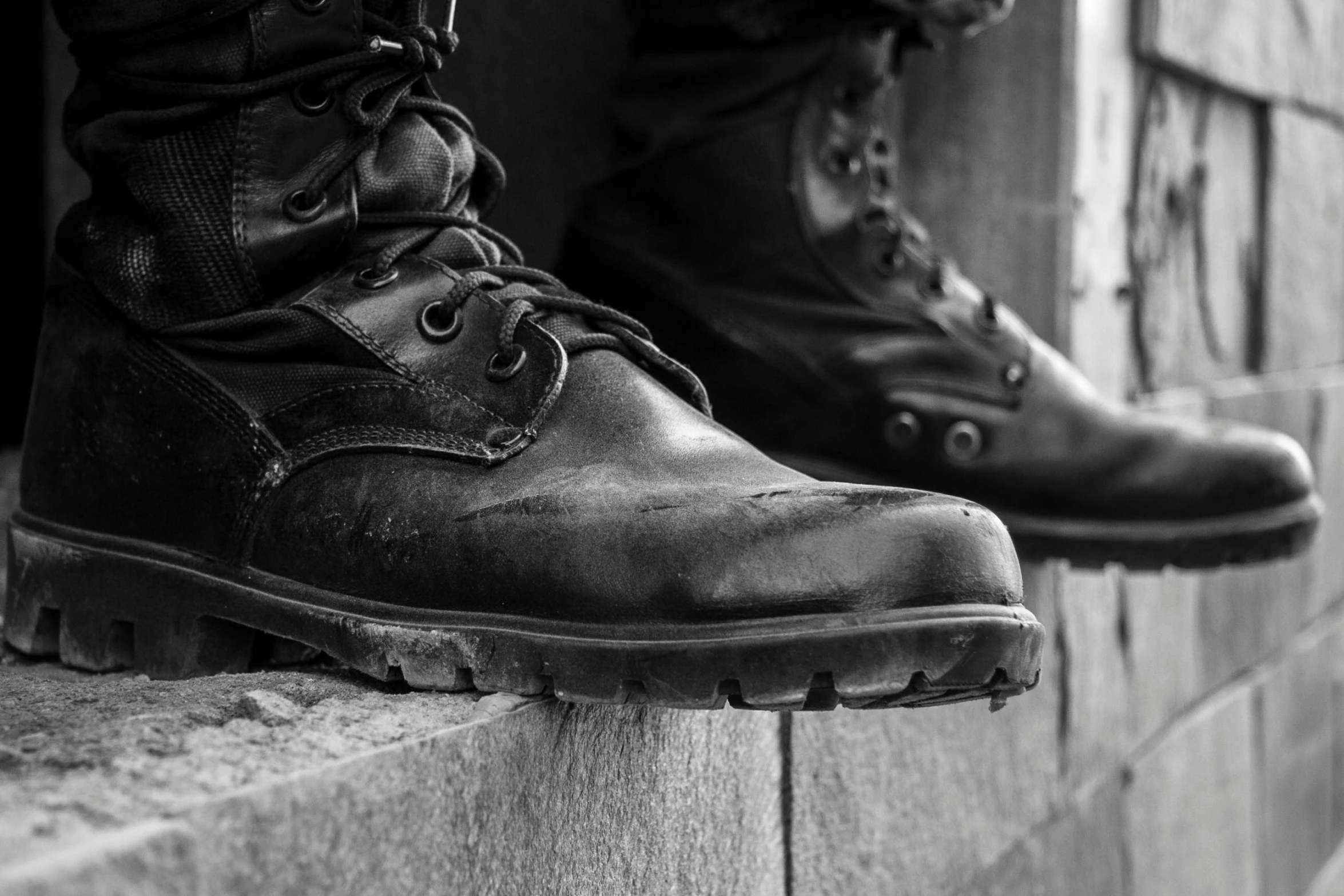 black and white po of an army boot on stone wall