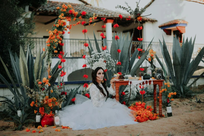 a woman sitting on the ground with flowers growing behind her