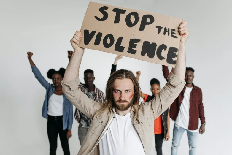 man in white shirt holding sign over head with protesters in background