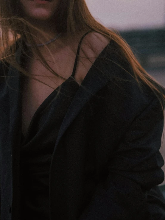 a woman in a black jacket, looking down and standing outdoors