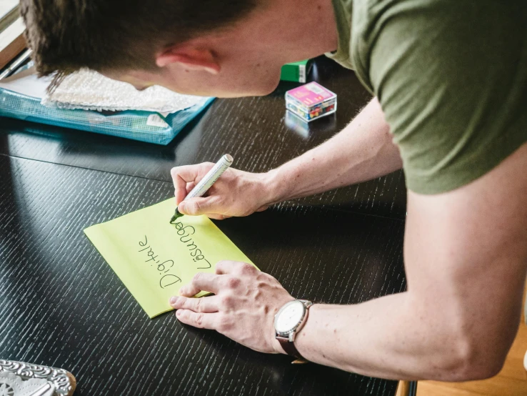 a man writing on a piece of paper while sitting at a table