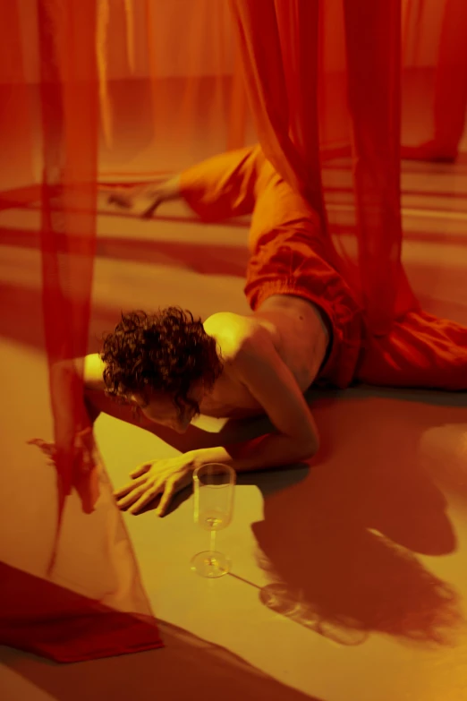a person in red is leaning on the floor with her head against the curtain