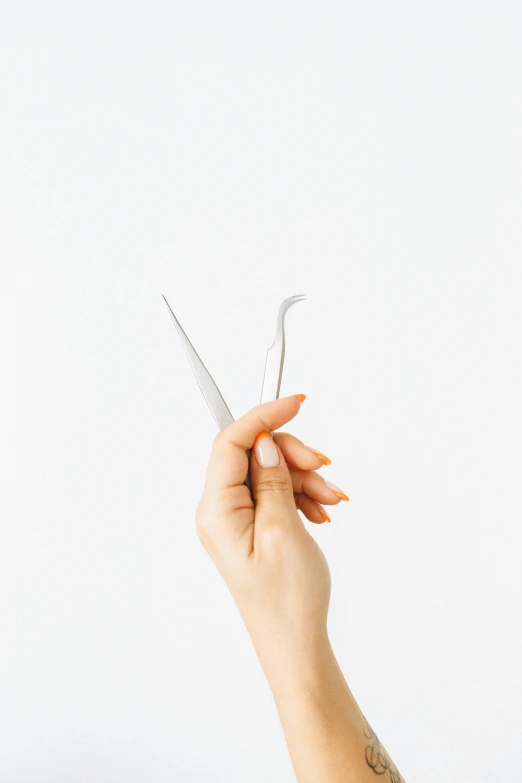 someones hand holding a pair of scissors in front of white background