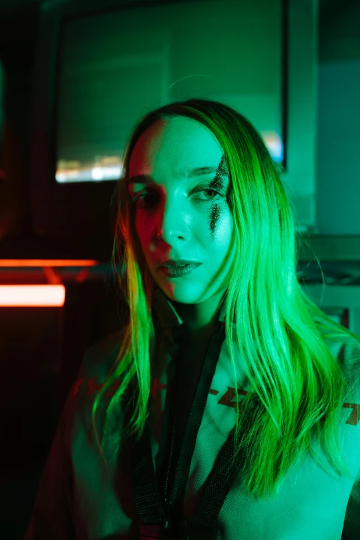 girl in green glow makeup standing in a dark room