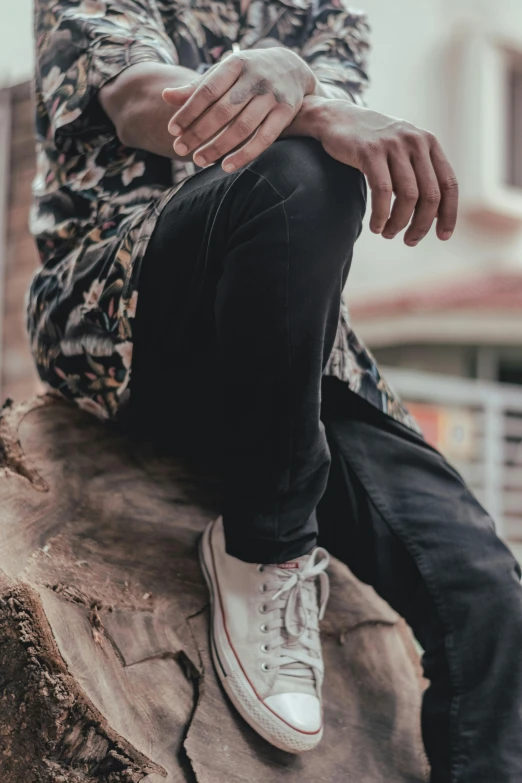 a man sitting on top of a large log with his hands crossed