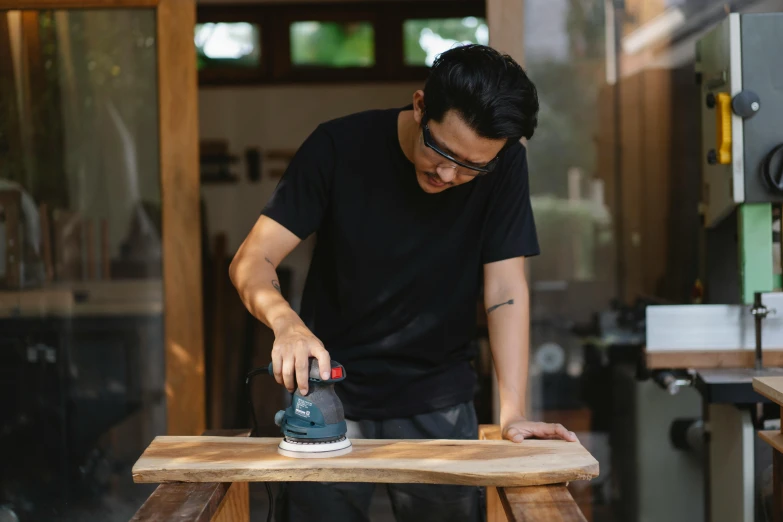 a man working with an electric sander on a piece of wood