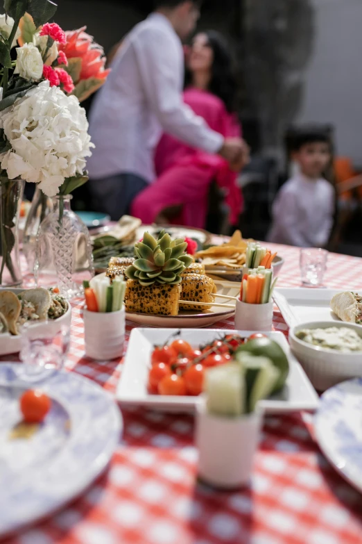 people sitting around a table with flowers, plates and utensils