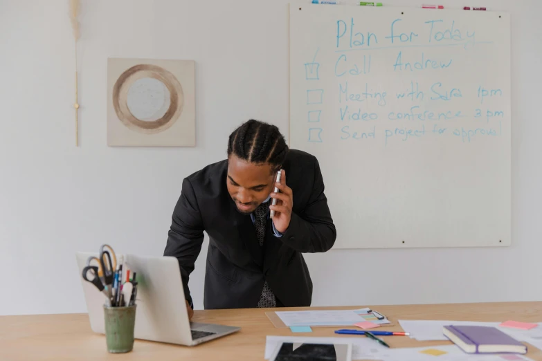 a man talking on his phone in front of his laptop