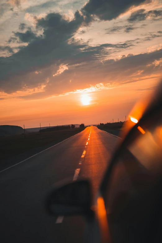 the sun is setting over the horizon as seen from a car's side window