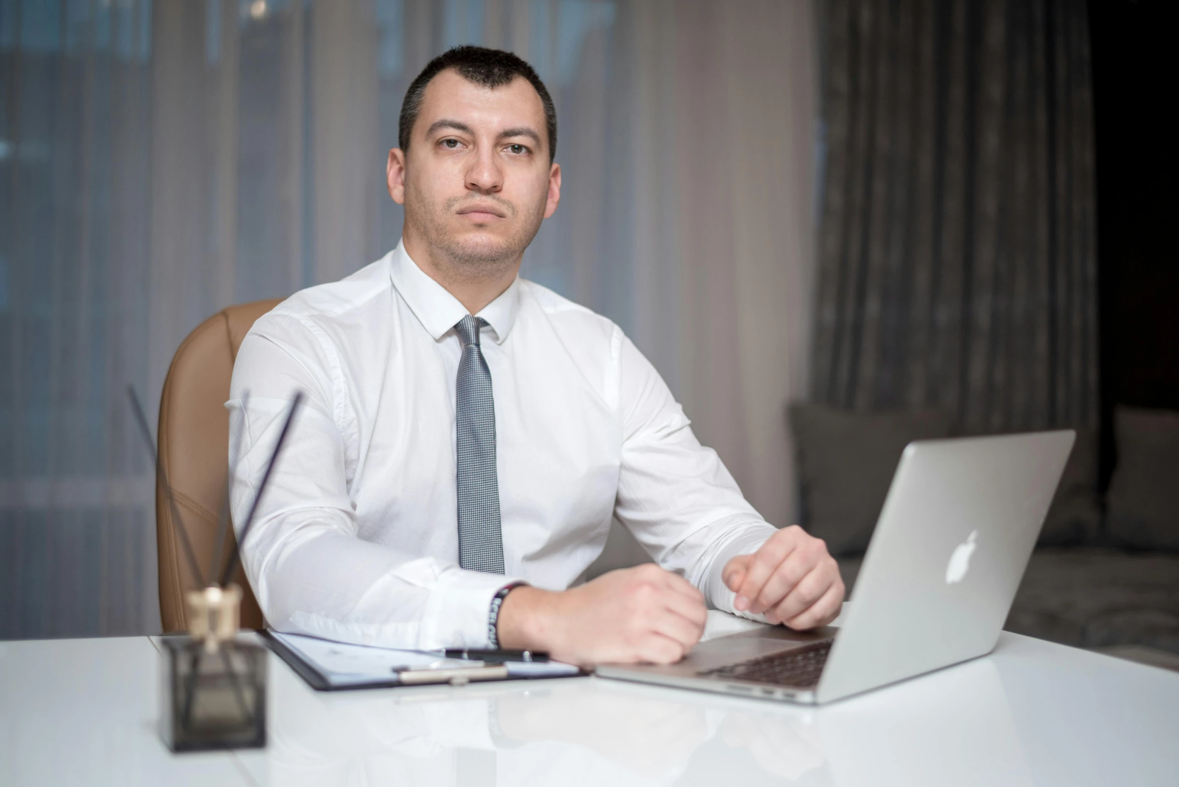 a man in dress clothes seated in front of his laptop