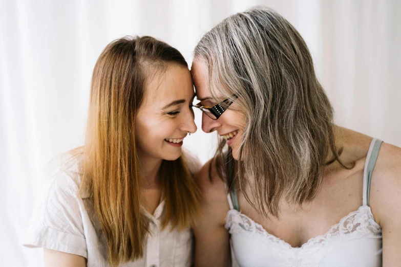 two woman with glasses are touching their faces together