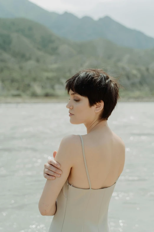 a woman in beige swimsuit sitting on shore