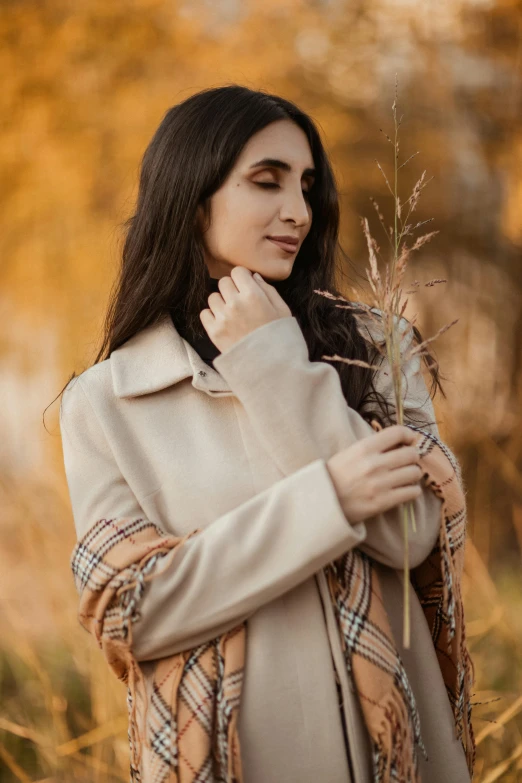 a woman holding a flower standing in the grass